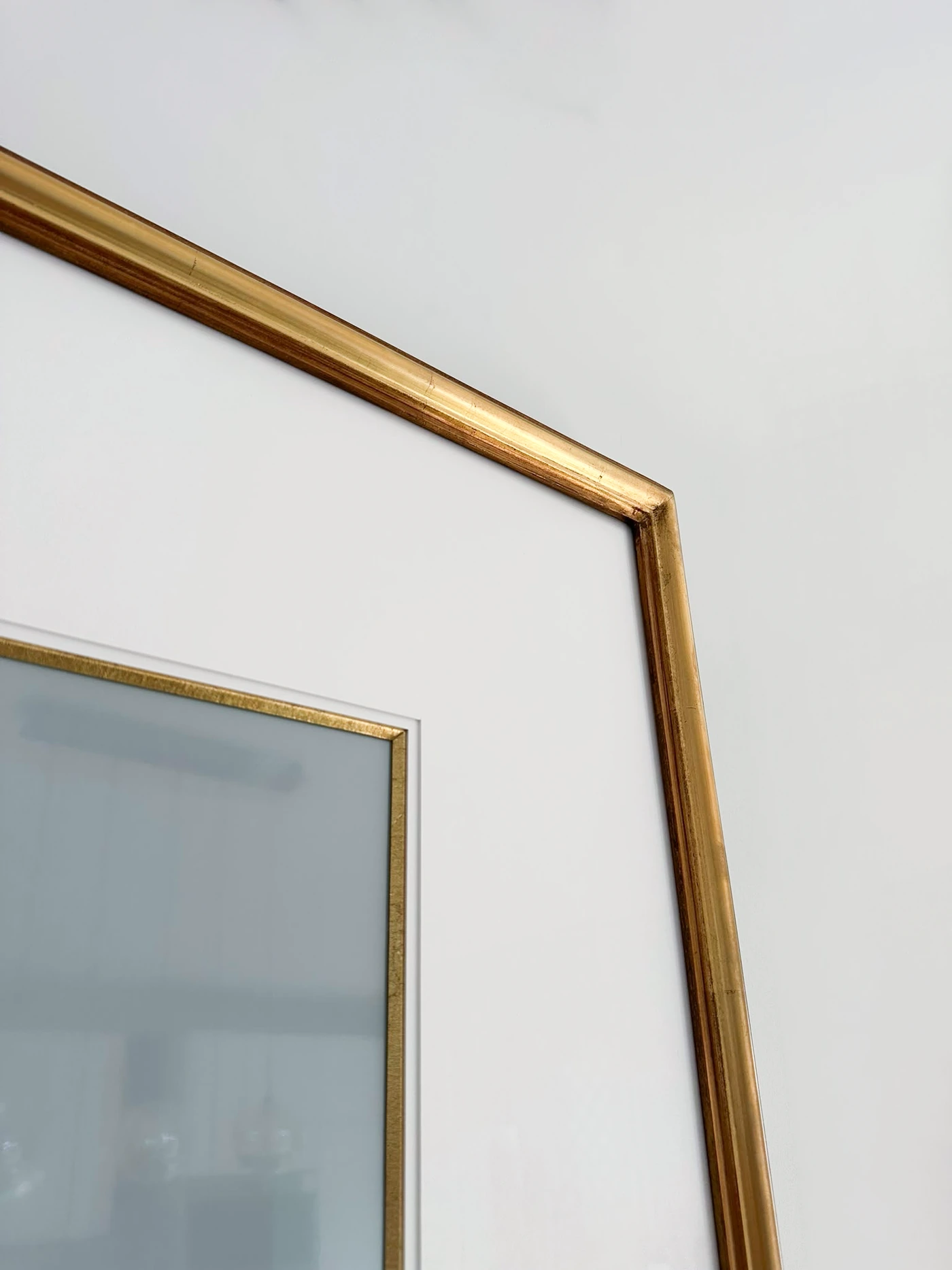 The corner of the gold-leaf moulding and the white mat.
