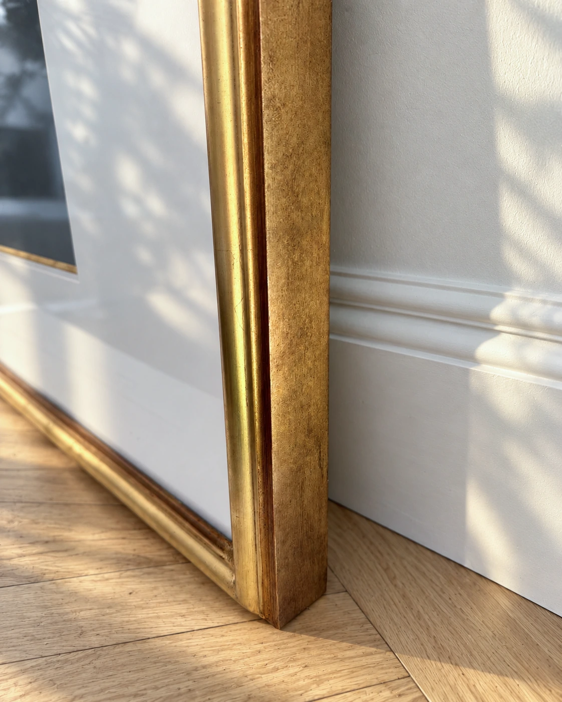 The profile of the gilded moulding, resting on the parquet.